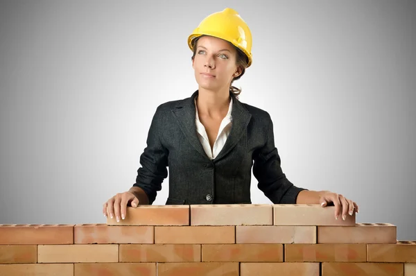 Jovem construtor feminino perto da parede de tijolo — Fotografia de Stock