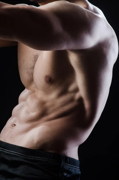 Muscular man posing in dark studio — Stock Photo, Image