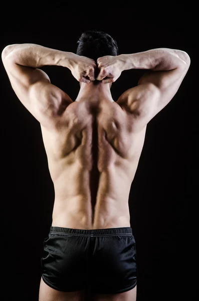 Muscular man posing in dark studio — Stock Photo, Image