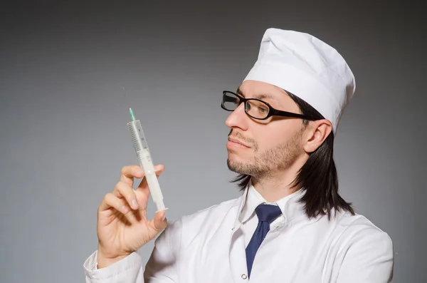 Jovem médico segurando seringa contra cinza — Fotografia de Stock