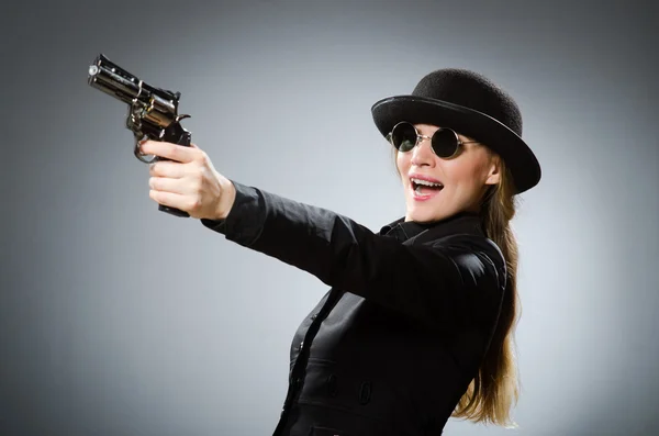 Female spy with weapon against gray — Stock Photo, Image