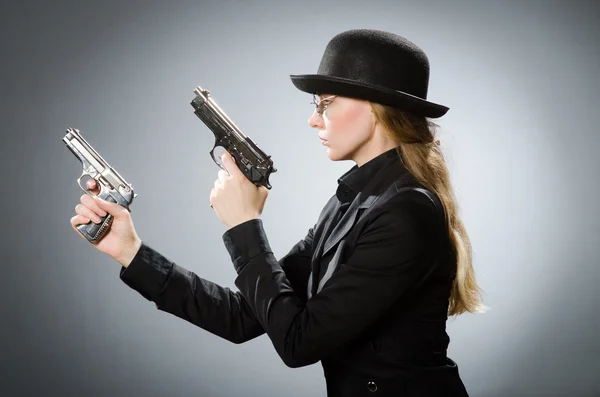 Female spy with weapon against gray — Stock Photo, Image