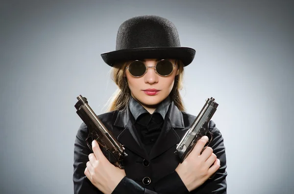Female spy with weapon against gray