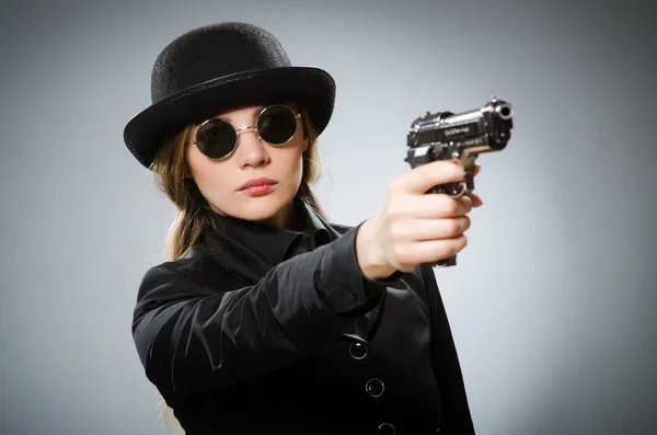 Kobieta szpieg z bronią przeciwko szarości — Zdjęcie stockowe