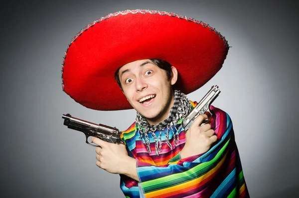 Hombre en vívido poncho mexicano sosteniendo pistola contra gris —  Fotos de Stock