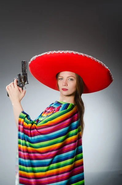 Girl in mexican vivid poncho holding handgun against gray — Stock Photo, Image