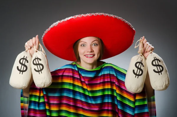 Девушка в мексиканском ярком пончо держит денежные мешки против серого — стоковое фото