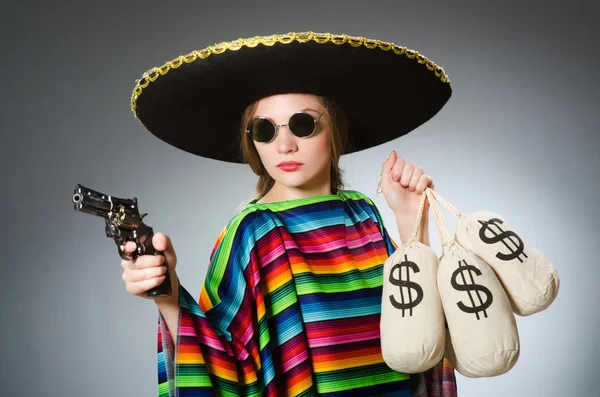 Девушка в мексиканском пончо держит пистолет и денежные мешки против г — стоковое фото