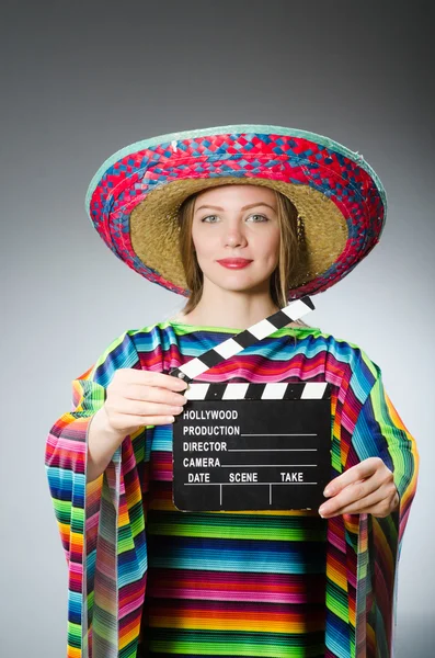 Девушка в мексиканском ярком пончо держит клапборд против серого — стоковое фото
