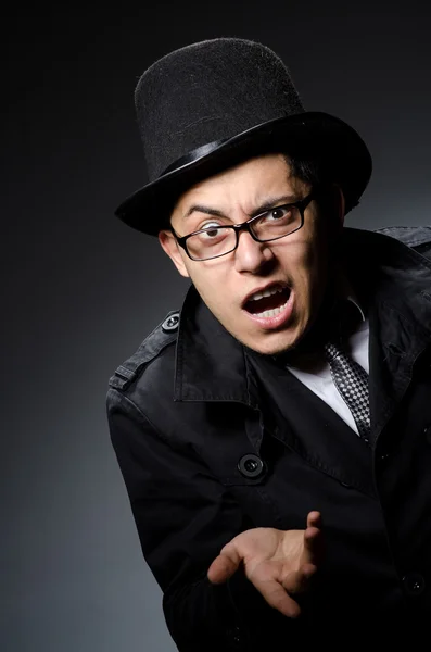 Joven con abrigo negro y sombrero contra gris — Foto de Stock