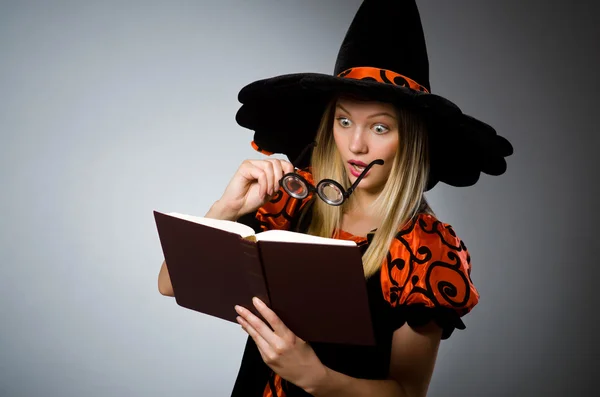 Witch with book in dark studio — Stock Photo, Image