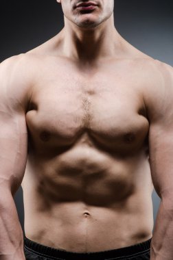 Kaslı adam karanlık stüdyoda poz veriyor.