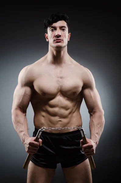 Mięśni mocny mężczyzna z nunchucks — Zdjęcie stockowe