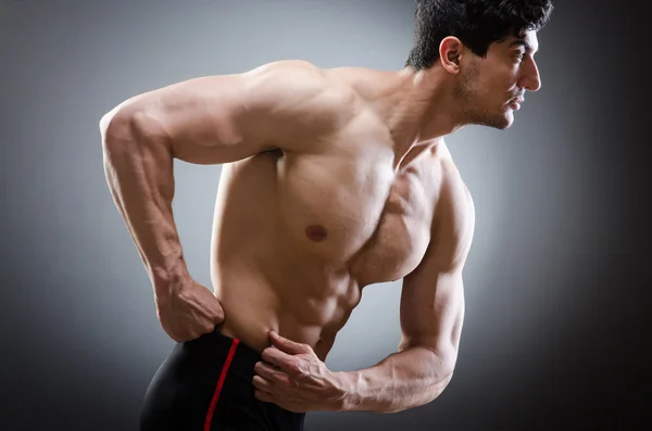 Muscular man posing in dark studio — Stock Photo, Image