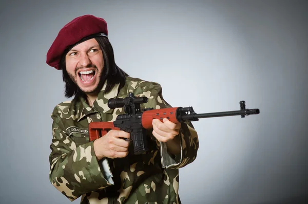 Soldado com pistola contra cinza — Fotografia de Stock