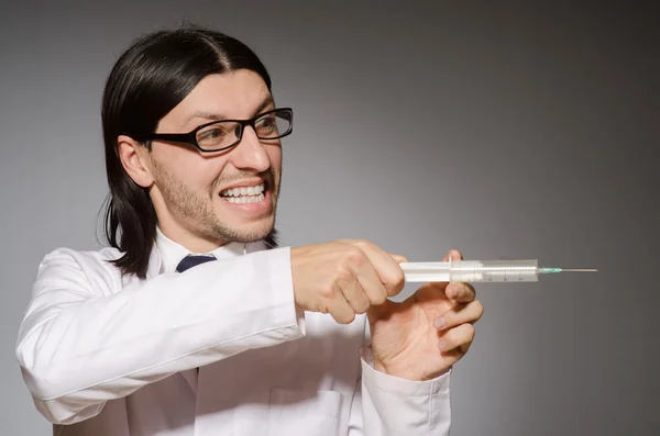 Joven médico sosteniendo jeringa contra gris — Foto de Stock