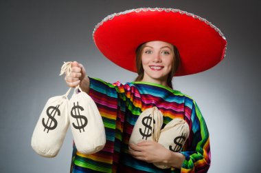 Girl in mexican vivid poncho holding money bags against gray clipart