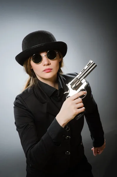 Kobieta szpieg z bronią przeciwko szary — Zdjęcie stockowe