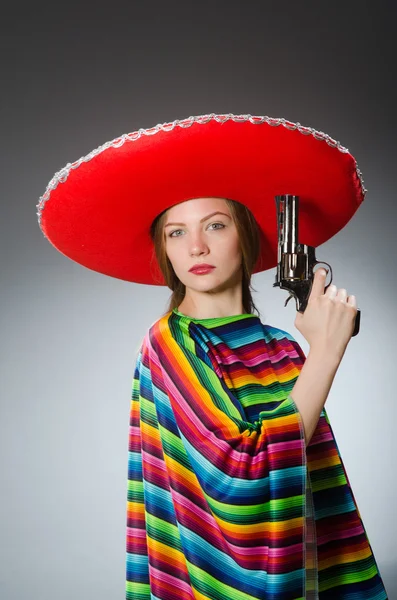Девушка в мексиканском ярком пончо держит пистолет против серого — стоковое фото
