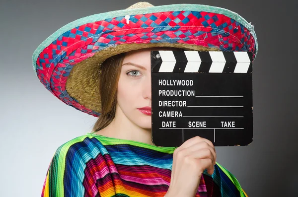 Chica en mexicano vívido poncho celebración clapboard contra gris —  Fotos de Stock