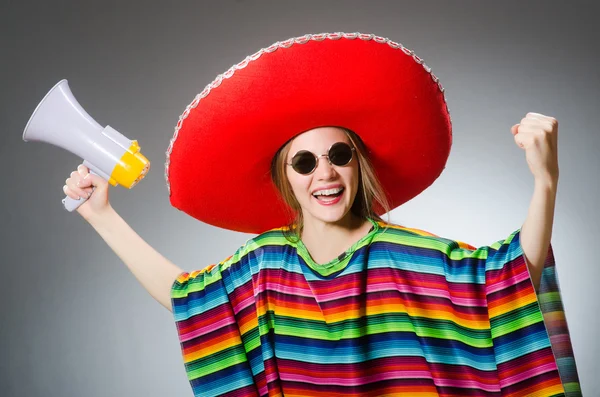 Girl in mexican vivid poncho holding loudspeaker against gray — Stock Photo, Image