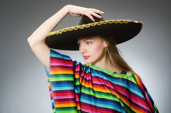 Дівчина в мексиканському яскравому пончо проти сірого — стокове фото