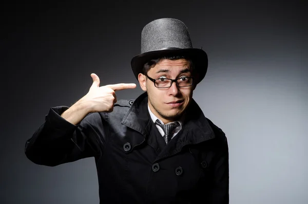 Joven con abrigo negro y sombrero contra gris — Foto de Stock