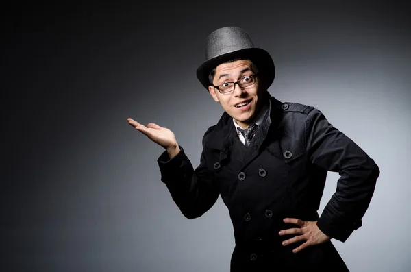 Joven con abrigo negro y sombrero contra gris — Foto de Stock