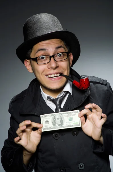 Young detective in black coat with money against gray — Stock Photo, Image