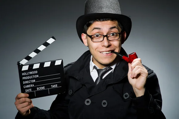 Detective de casaco preto com clapperboard contra cinza — Fotografia de Stock