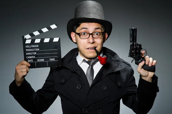 Detective in black coat with clapperboard against gray — Stock Photo, Image