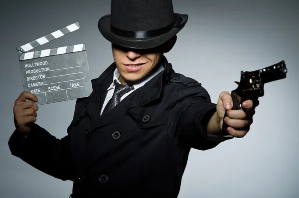 Young man with weapon and clapboard against gray — Stock Photo, Image