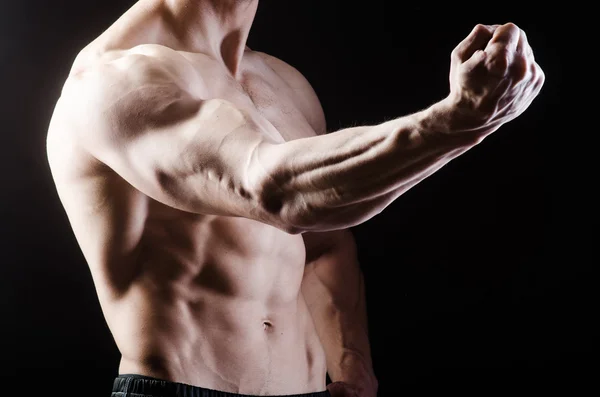 Hombre musculoso posando en estudio oscuro — Foto de Stock