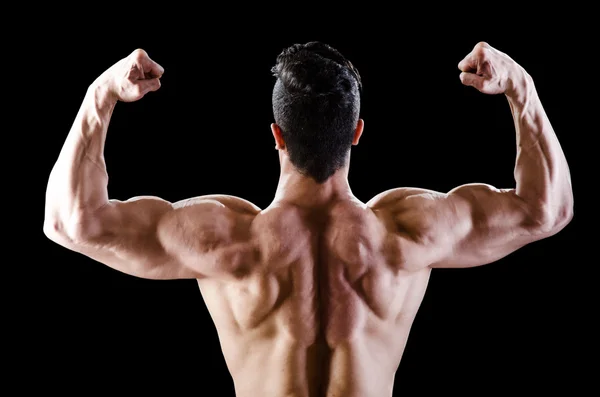 Muscular man posing in dark studio — Stock Photo, Image