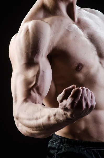 М'язистий чоловік позує в темній студії — стокове фото