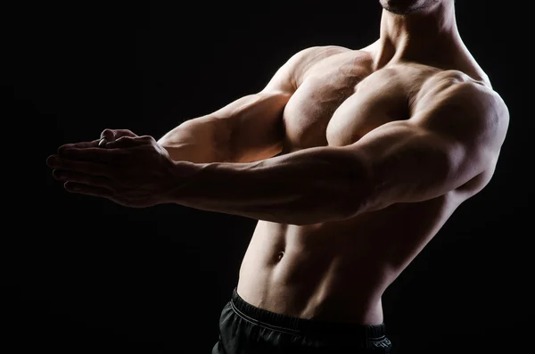 Muscular man posing in dark studio — Stock Photo, Image