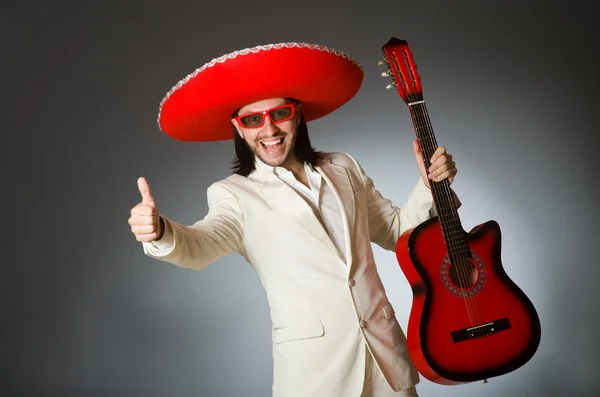 Смешной мексиканец в костюме держит гитару против серого — стоковое фото