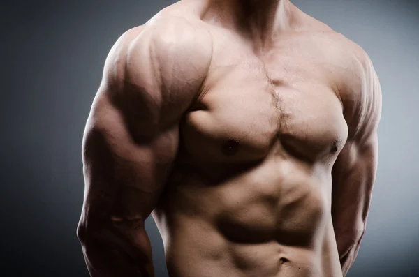 Muscular man posing in dark studio — Stock Photo, Image