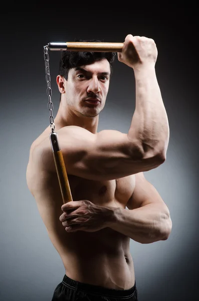 Muscular strong man with nunchucks — Stock Photo, Image