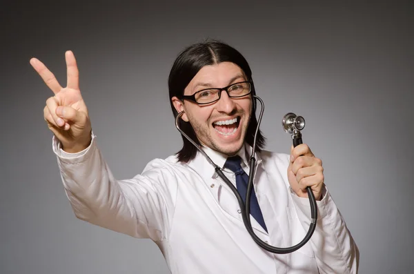 Médico joven con estetoscopio contra gris —  Fotos de Stock