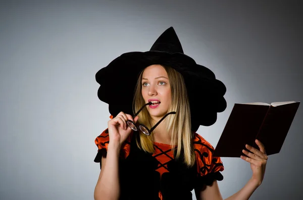 Witch with book in dark studio — Stock Photo, Image