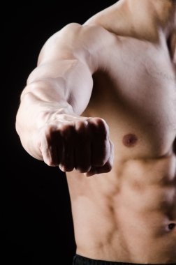 Kaslı adam karanlık stüdyoda poz veriyor.