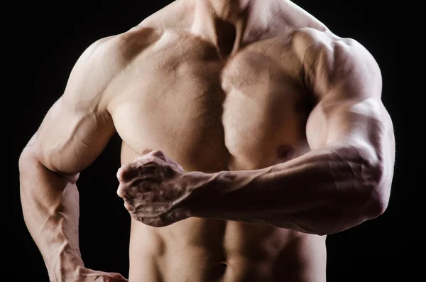 Hombre musculoso posando en estudio oscuro — Foto de Stock