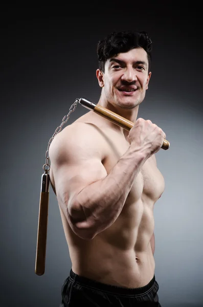 Musculoso hombre fuerte con nunchucks — Foto de Stock