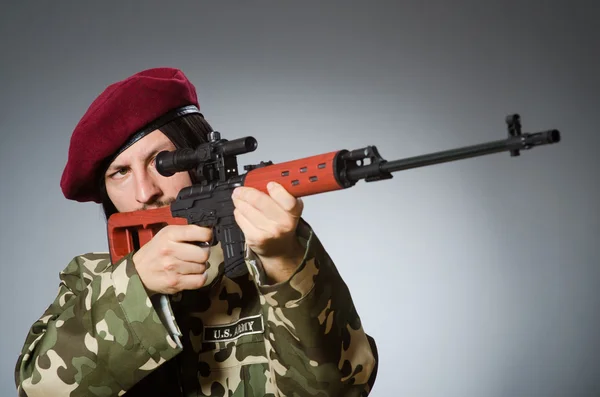 Soldado com pistola contra cinza — Fotografia de Stock