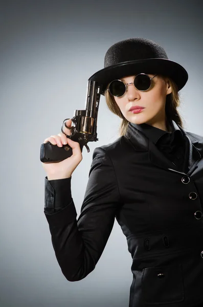 Female spy with weapon against gray