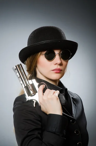 Vrouwelijke spion met wapen tegen grijs — Stockfoto