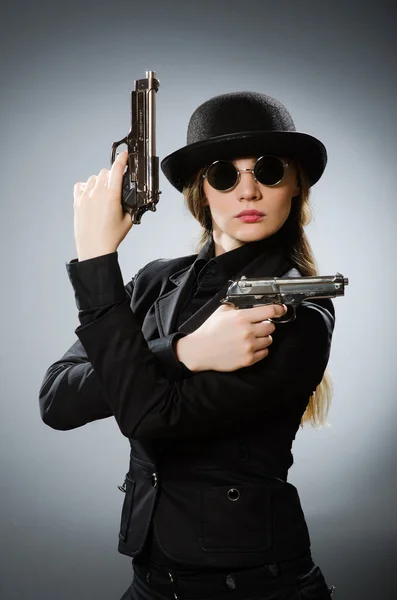 Kobieta szpieg z bronią przeciwko szarości — Zdjęcie stockowe