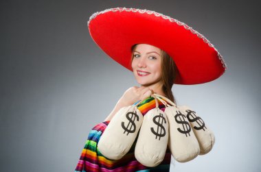 Girl in mexican vivid poncho holding money bags against gray clipart