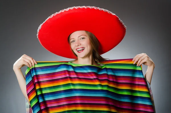 Дівчина в мексиканському яскравому пончо проти сірого — стокове фото